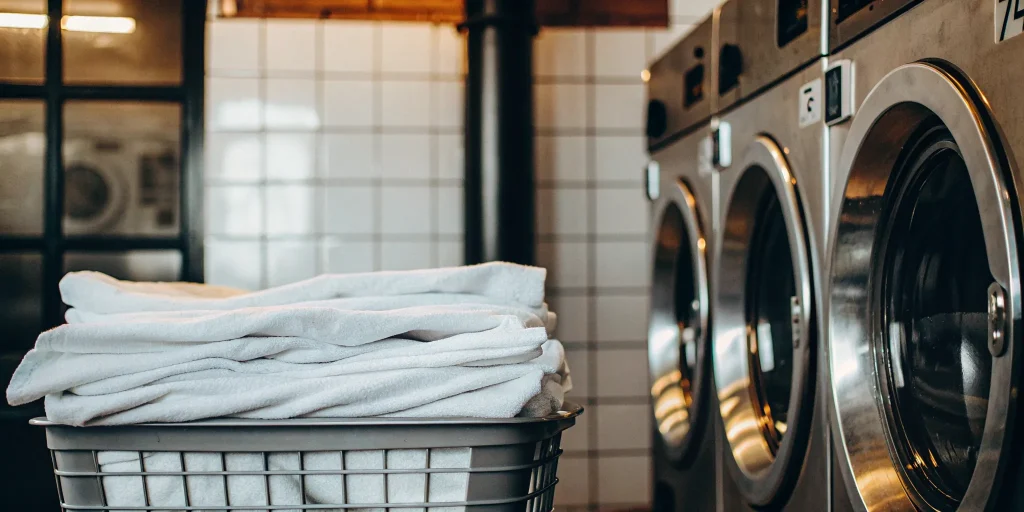 Basket of clean linens at a Carle Place medical laundry facility with industrial washers.